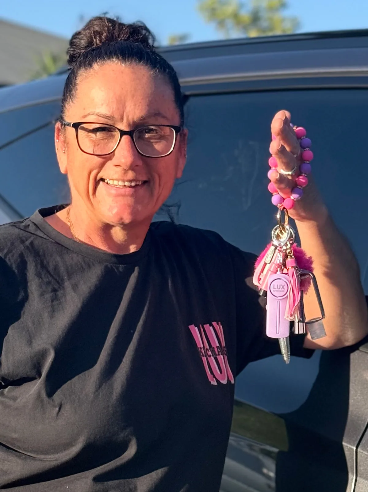 Ruth, founder of LUX Keychains, smiling and holding a pink and purple beaded safety keychain